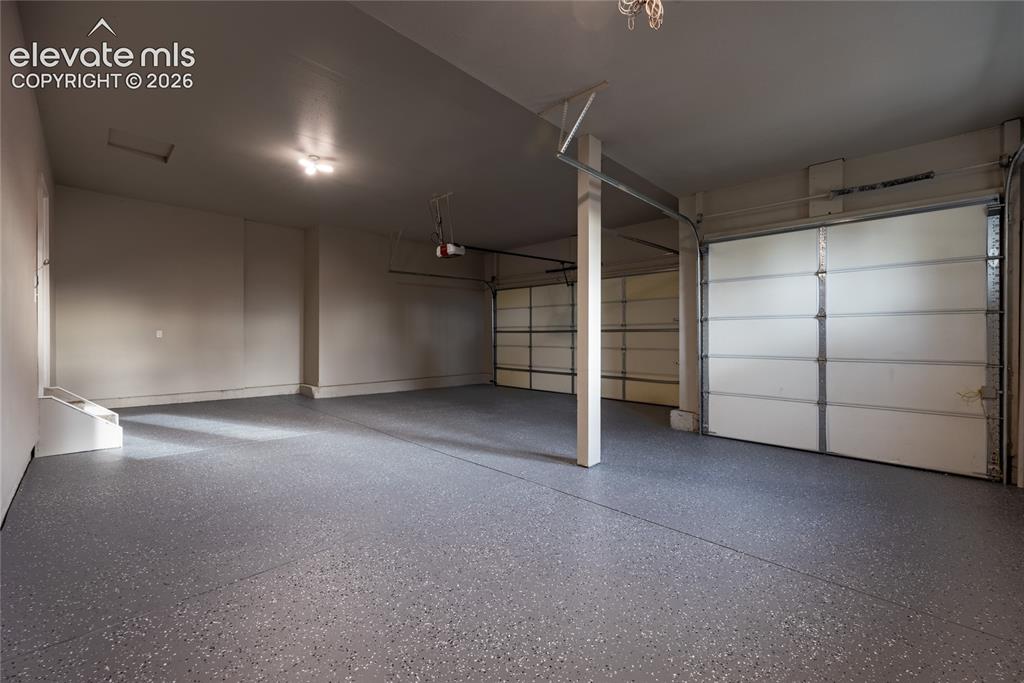 Image 45 of 48: Spacious garage with two overhead doors and an epoxy flake floor