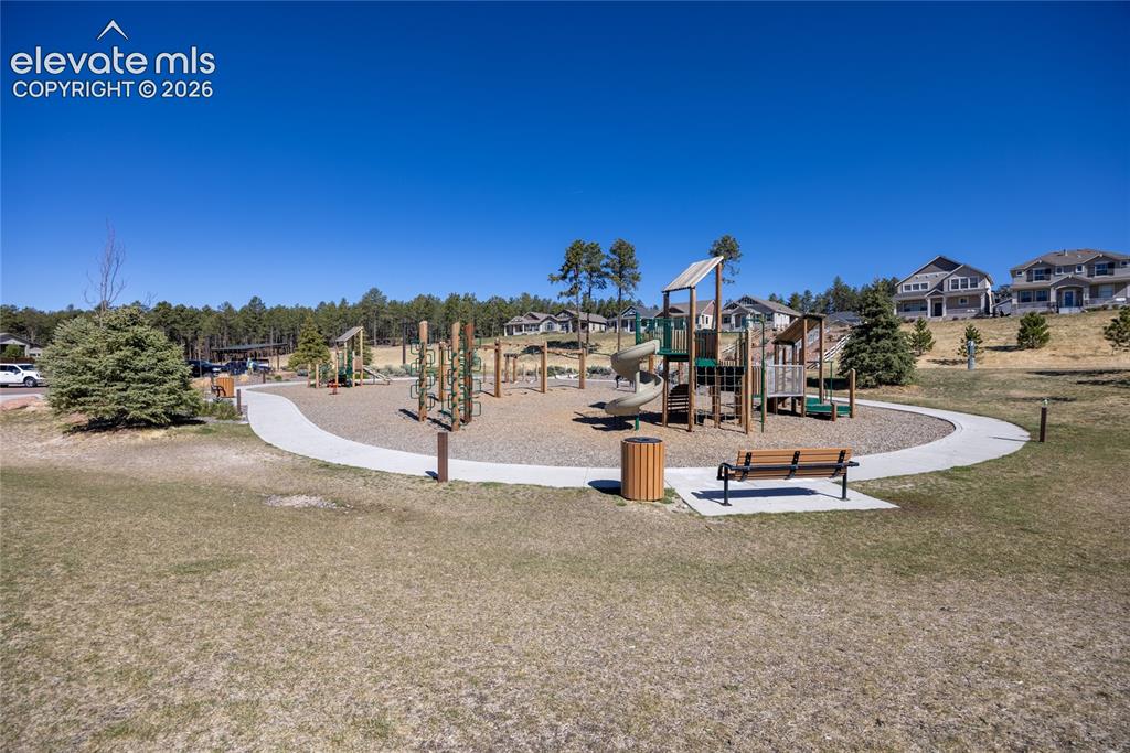 Image 47 of 48: Expansive community playground featuring multiple play structures, a paved 