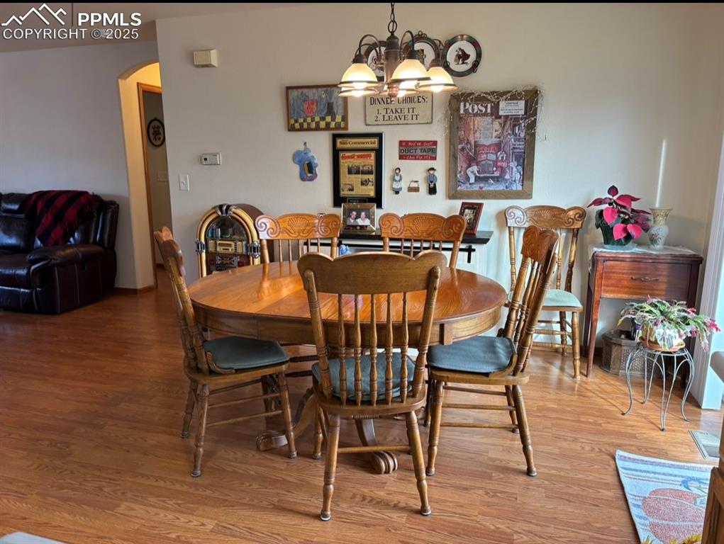 Image 5 of 15: Dining room featuring arched walkways, wood finished floors, and a chandeli