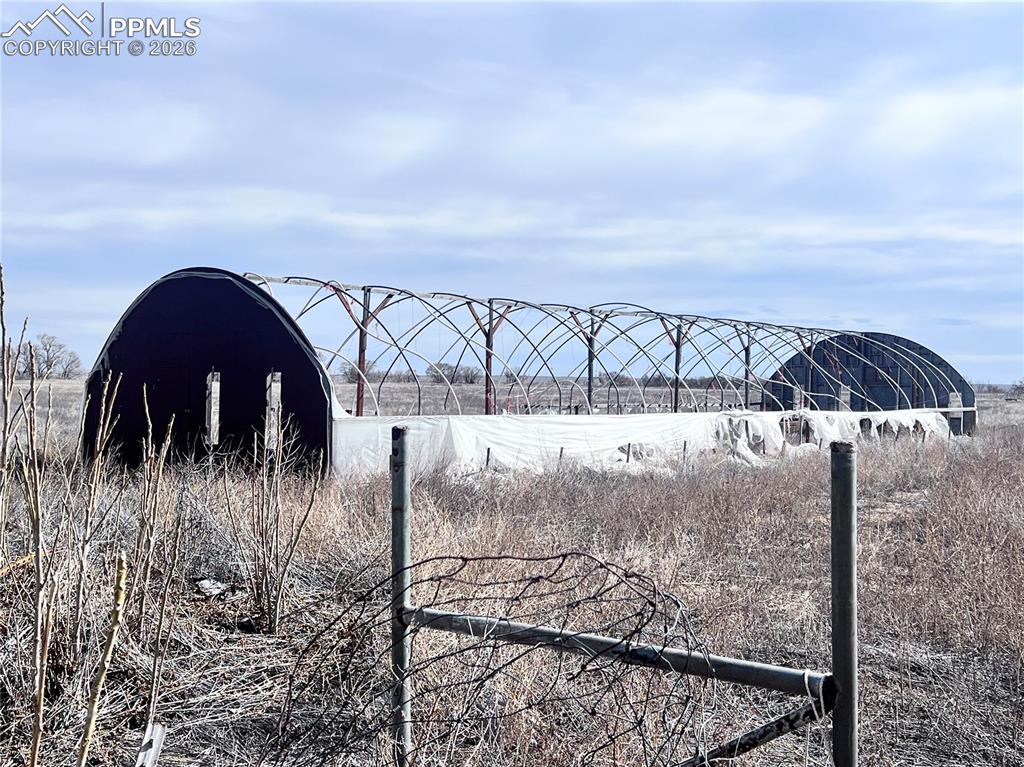 Image 21 of 33: The property features a natural dirt path, surrounded by expansive grasslan