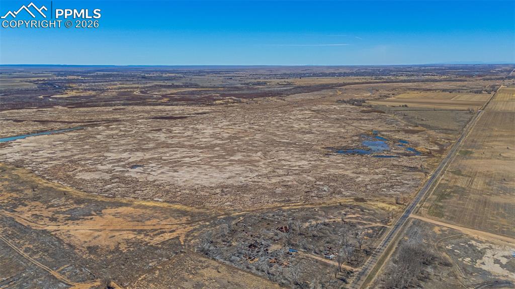 Image 31 of 33: Extensive rural property featuring vast open fields, a visible dirt road, a