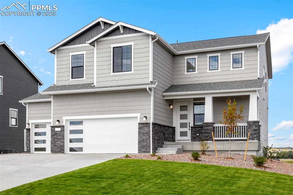 Caption: Craftsman-style home with driveway, stone siding, covered porch, an attached garage, and a front yar