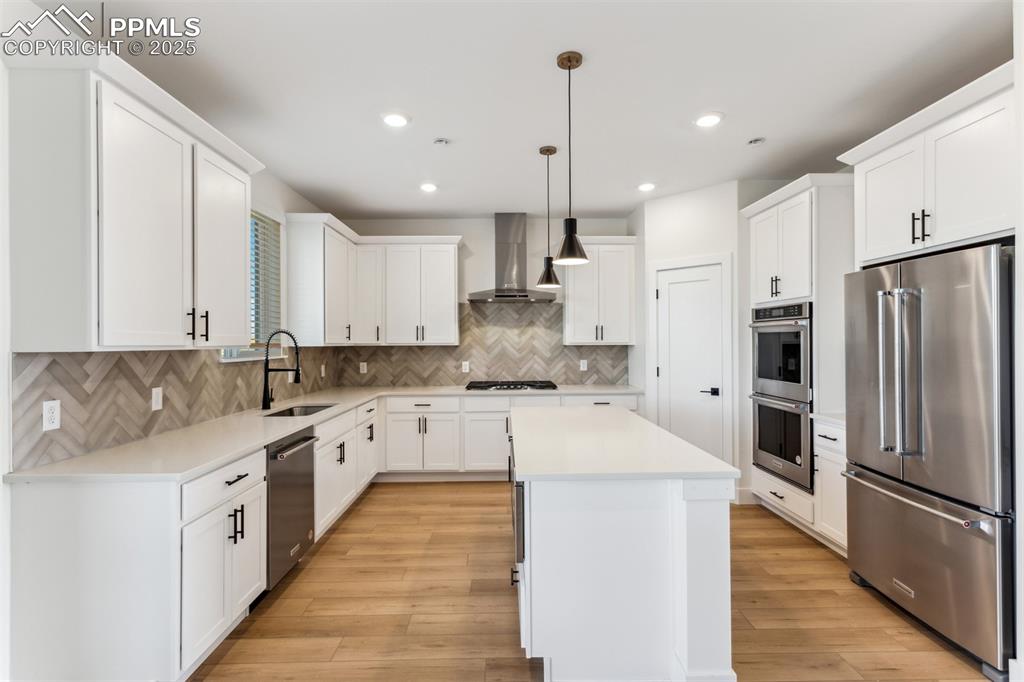 Image 5 of 20: Kitchen featuring wall chimney exhaust hood, a sink, appliances with stainl