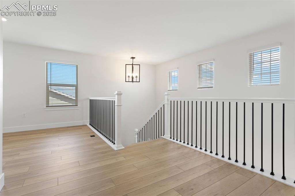 Image 6 of 20: Spare room with a chandelier, light wood-type flooring, and baseboards