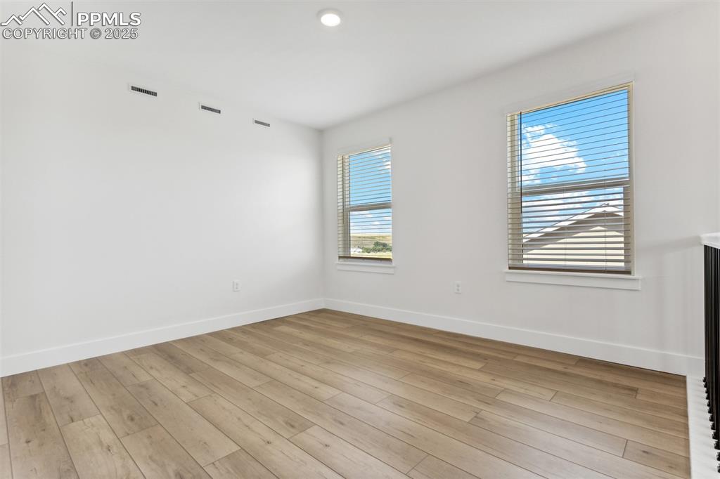 Image 7 of 20: Empty room with light wood-type flooring, baseboards, and visible vents