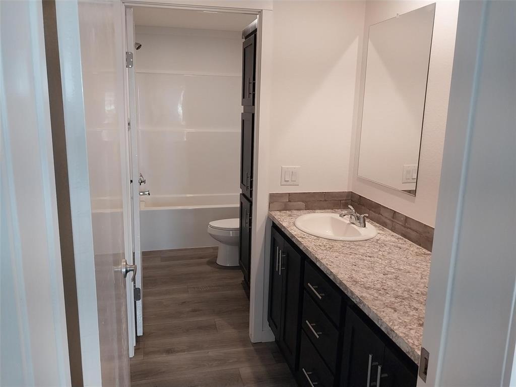 Image 12 of 25: Full bathroom featuring vanity, dark wood-type flooring, and  shower combin