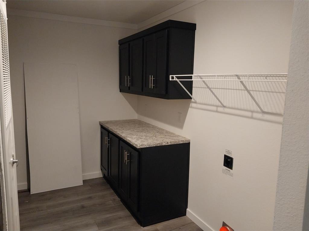 Image 13 of 25: Laundry room with dark wood-style floors, cabinet space, and ornamental mol
