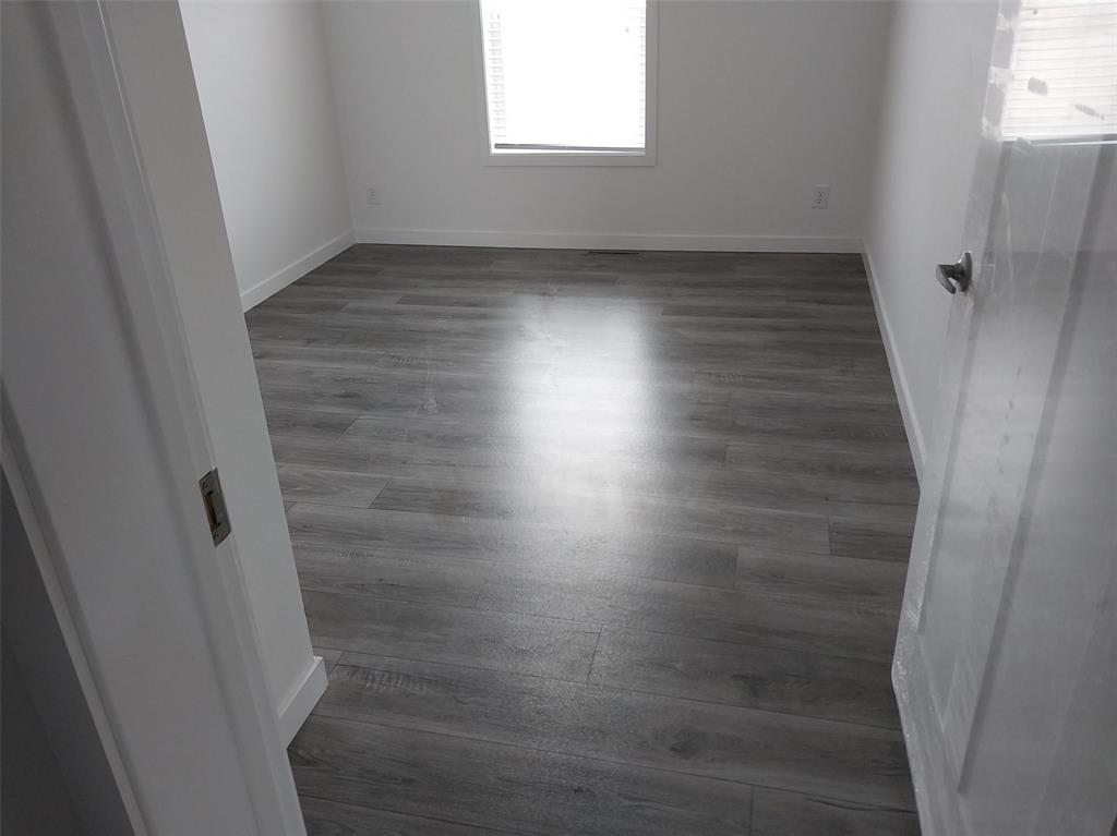 Image 23 of 25: Empty room with baseboards and dark wood finished floors