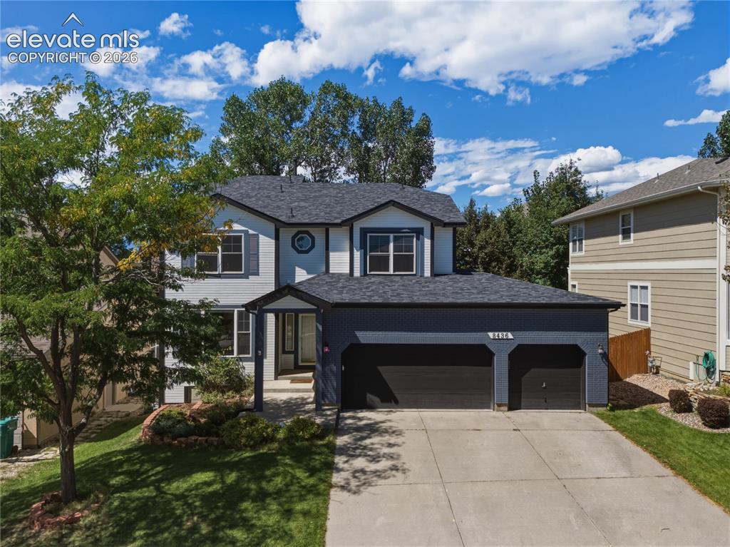 Caption: Two-story residence with a two-car garage, concrete driveway, and front yard landscaping