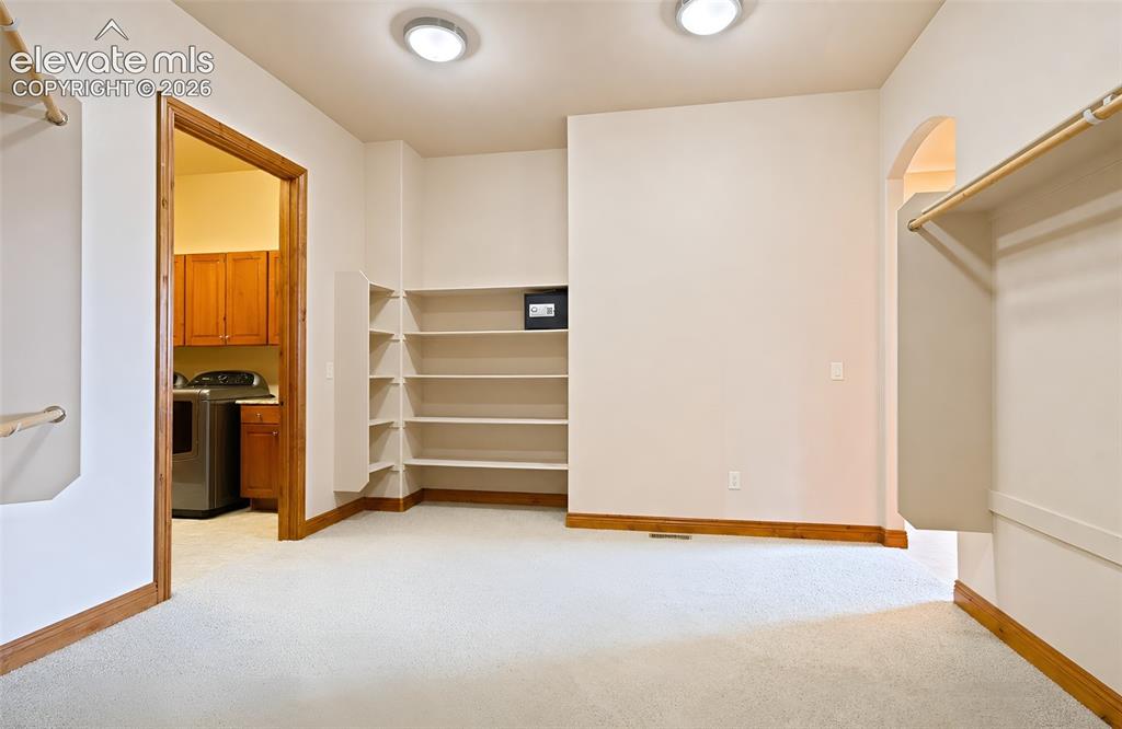 Image 29 of 48: Primary bedroom walk in closet with laundry to the left