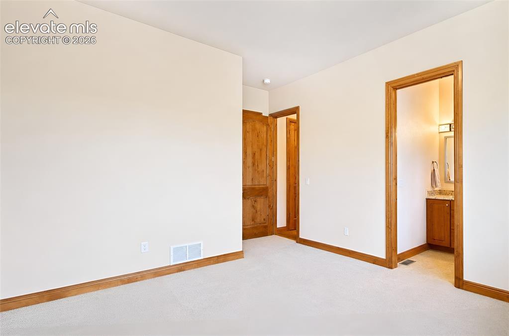 Image 43 of 48: Main level guest bedroom near front entry with en-suite 3/4 bathroom
