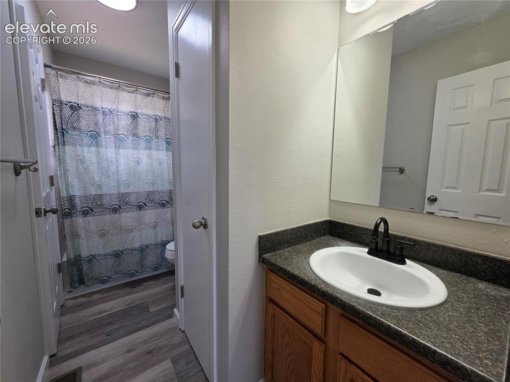 Image 10 of 18: Bathroom featuring a wood-finish vanity with a dark countertop, white oval 