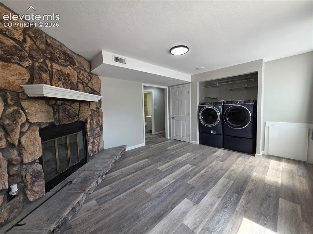 Image 14 of 18: Stone-clad fireplace with mantel, wood-finish flooring, recessed lighting,