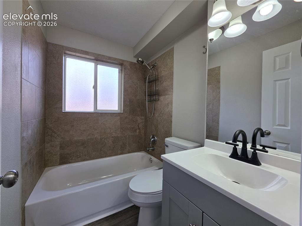 Image 17 of 18: Wood-finish flooring with a white bathtub and tiled shower surround