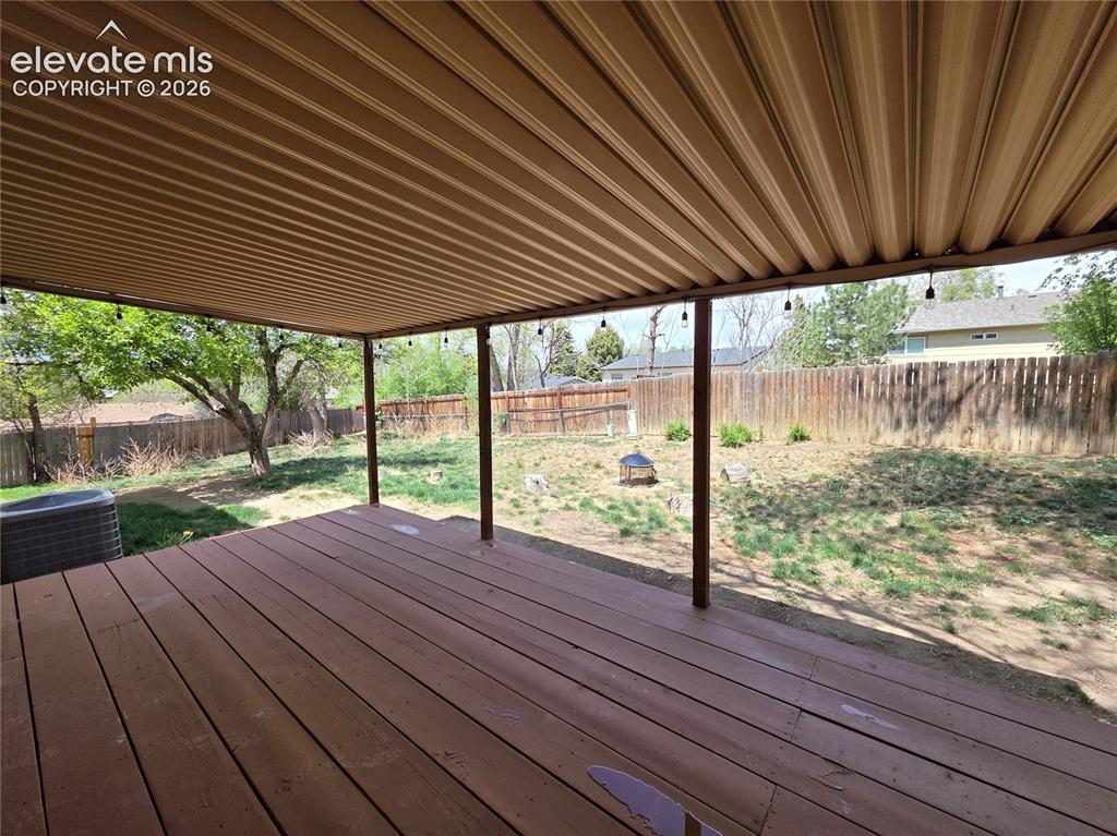 Image 18 of 18: Expansive covered patio featuring a corrugated metal roof and wood-finish d