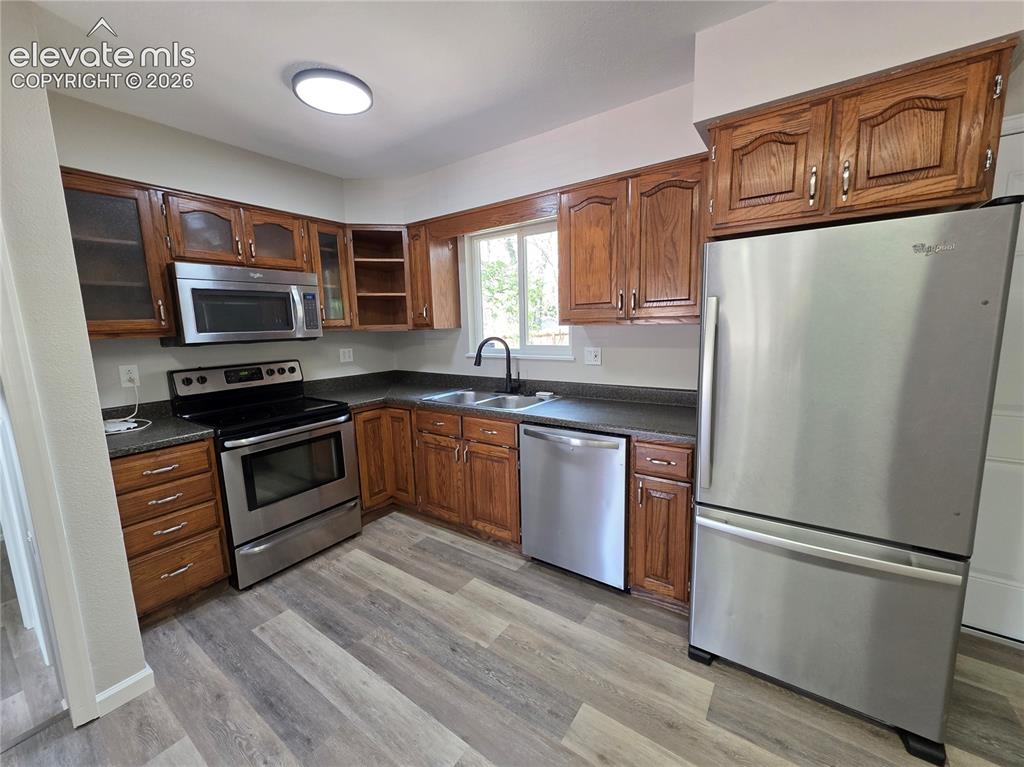 Image 5 of 18: Kitchen featuring wood cabinetry, stainless steel appliances, dark countert