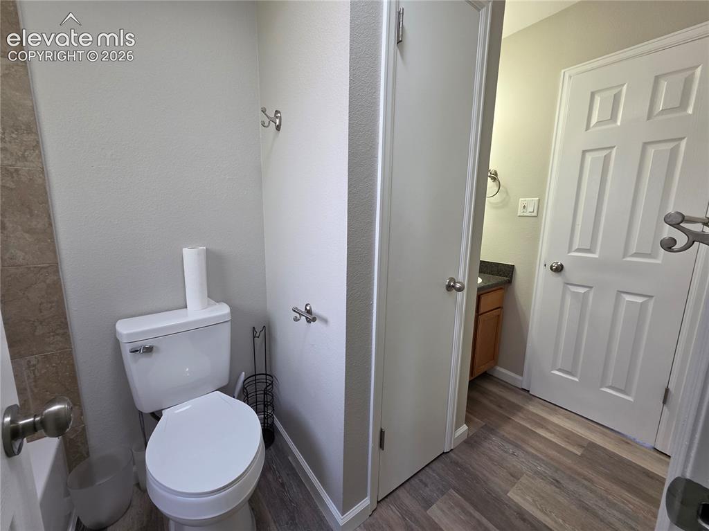 Image 9 of 18: Wood-finish flooring with a light gray wall color, paneled door, and a toil