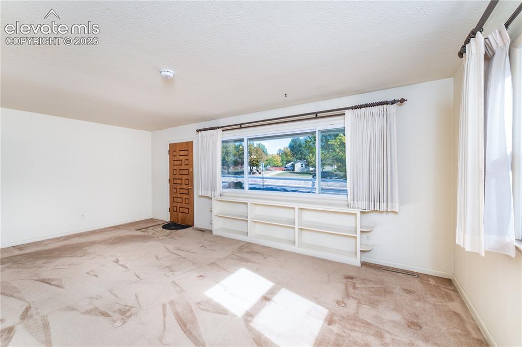 Image 11 of 29: Large window with built-in shelving, patterned wood entry door, and light-c