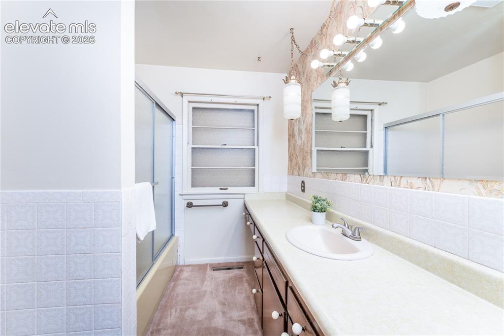 Image 13 of 29: Extended vanity with integrated sink, full-width mirror, and multi-bulb van