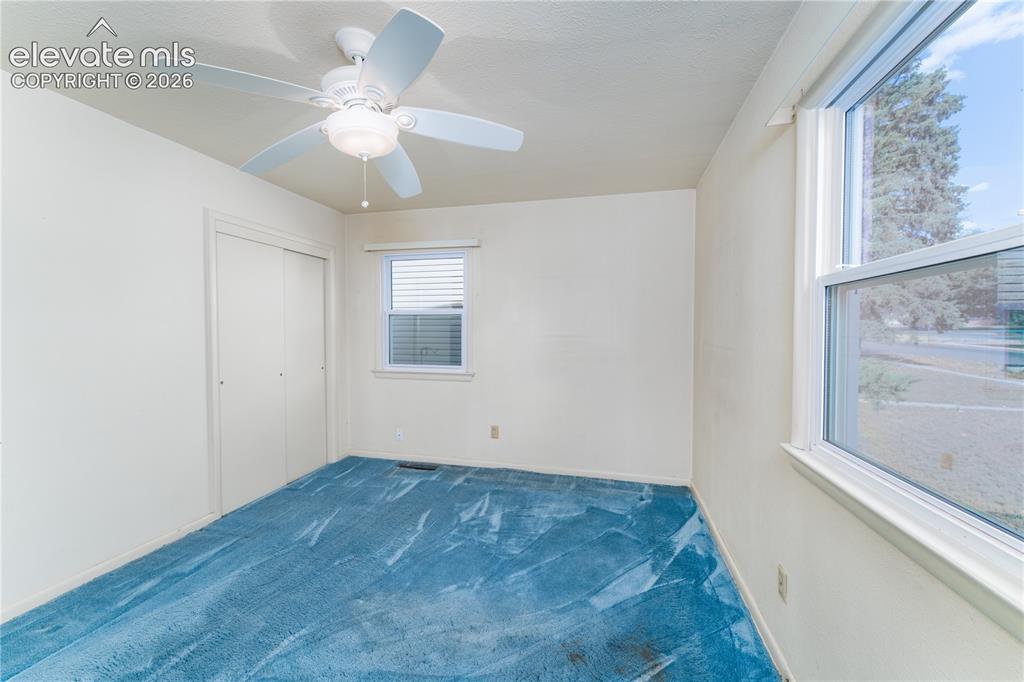 Image 15 of 29: Room featuring a ceiling fan, two windows with white trim, and a built-in c