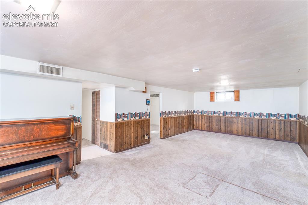 Image 20 of 29: Spacious room featuring carpeted flooring and wood-paneled wainscoting