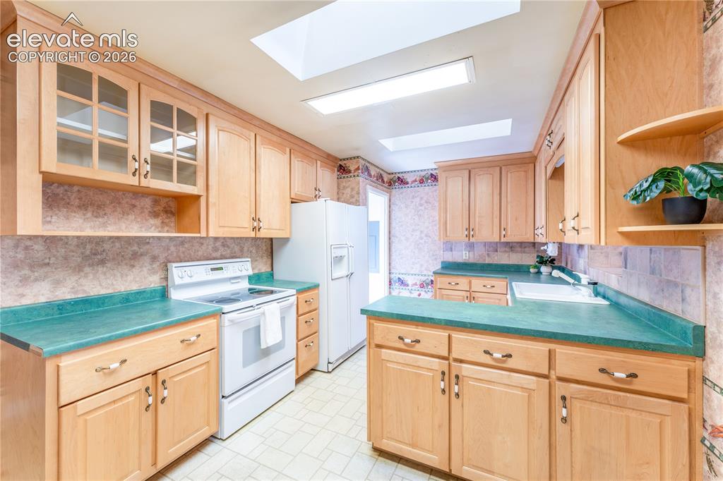 Image 3 of 29: Kitchen featuring wood cabinetry, green countertops, and skylights