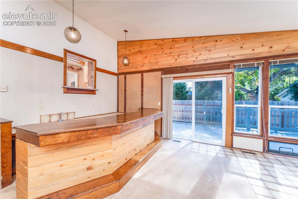 Image 4 of 29: Built-in wood-finish bar with shelving, vaulted wood-plank ceiling, sliding