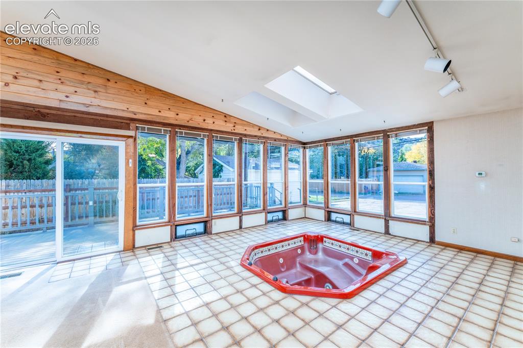 Image 5 of 29: Integrated red spa tub with tiled surround, vaulted ceiling with wood panel