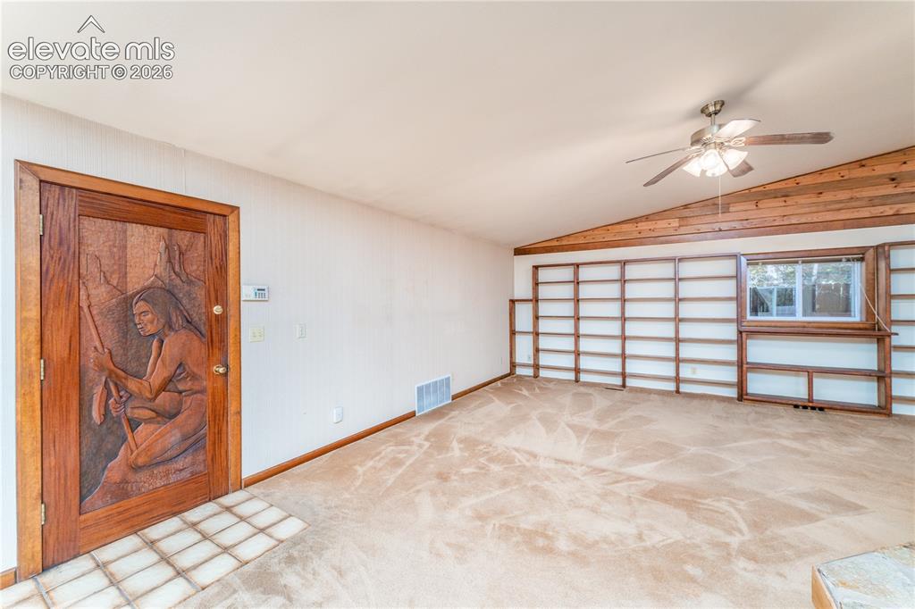 Image 8 of 29: Vaulted ceiling with wood paneling, ceiling fan, expansive built-in shelvin