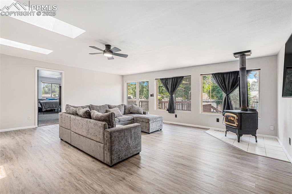 Image 18 of 35: Living area with a skylight, plenty of natural light, a wood stove, and woo
