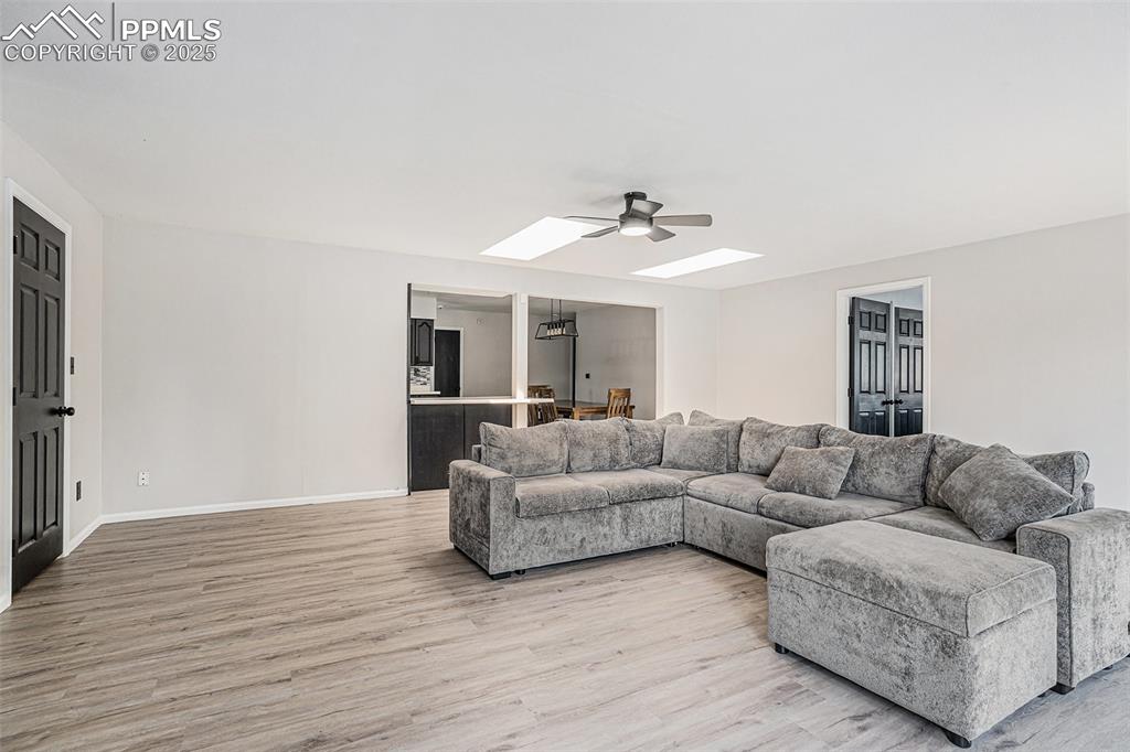 Image 20 of 35: Living area with a skylight, a ceiling fan, and light wood-style floors