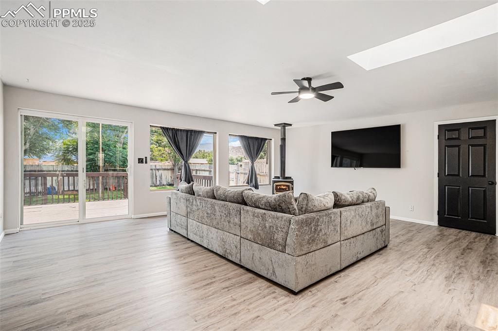 Image 22 of 35: Living area featuring a wood stove, ceiling fan, and two skylights