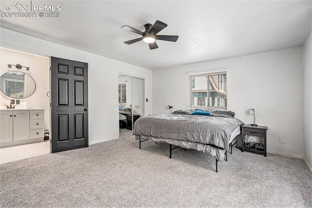 Image 24 of 35: Bedroom with light colored carpet, a closet, ceiling fan, and ensuite bathr