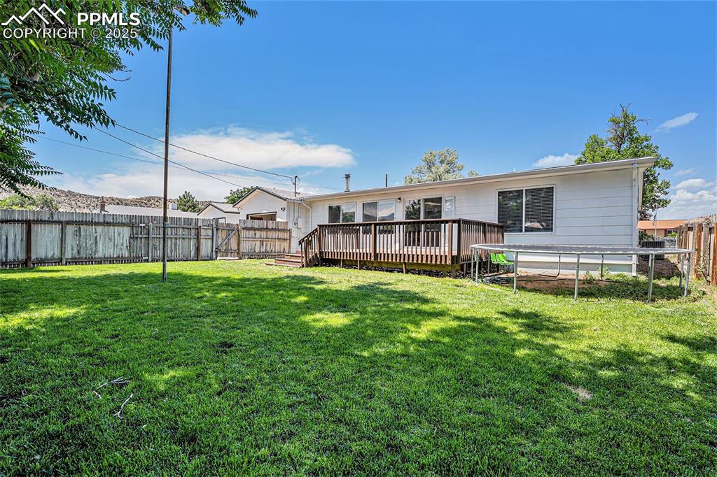 Image 34 of 35: Back of property with a trampoline, a fenced backyard, and a wooden deck