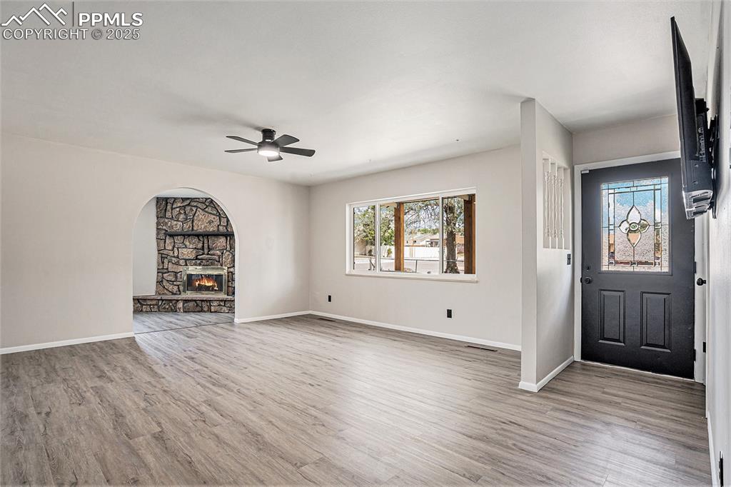 Image 6 of 35: Entrance foyer featuring ceiling fan, arched walkways, and a stone fireplac