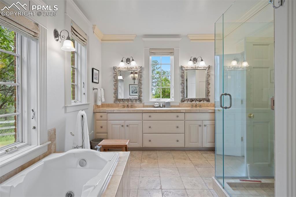 Image 20 of 49: Spa-like primary bath with jetted soaking tub, sunlit windows, and dual van