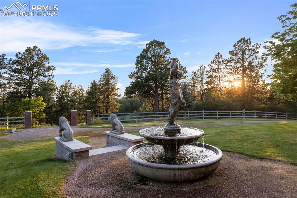 Image 27 of 49: Evening light dances on the fountain, casting a golden glow over the gated 