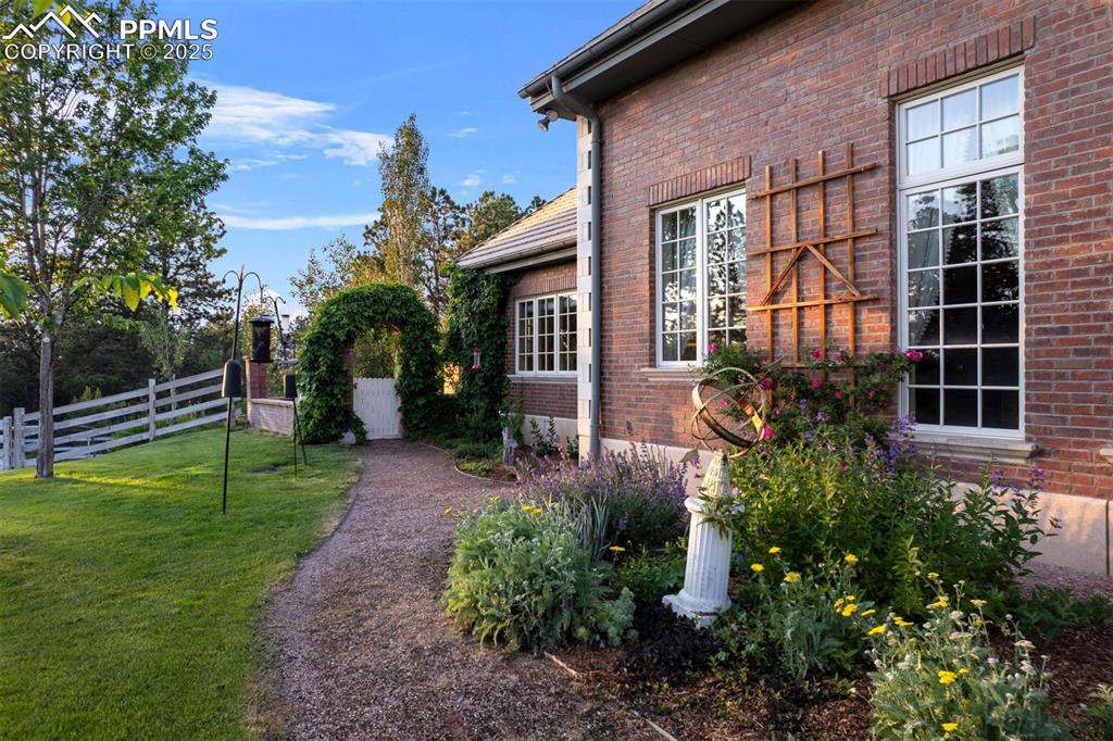 Image 29 of 49: Perennial gardens burst with color along a winding path that leads to ivy-w