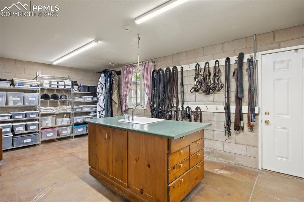 Image 35 of 49: Spacious tack and feed room with an exterior door to the courtyard, island 