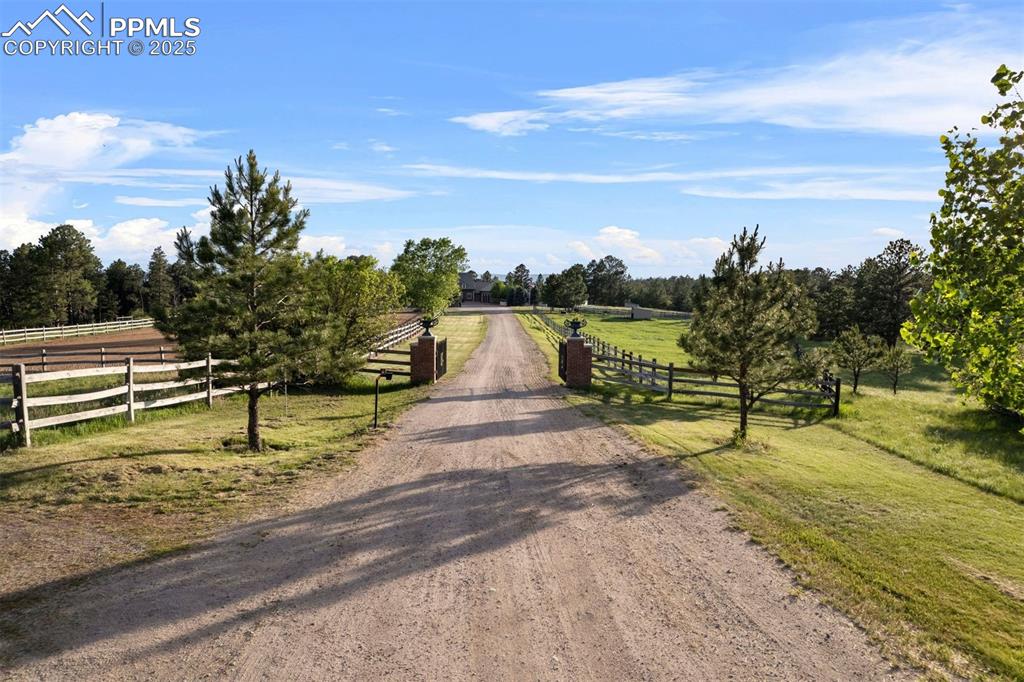 Image 48 of 49: A beautiful gated entry welcomes you to the property, with well-maintained 