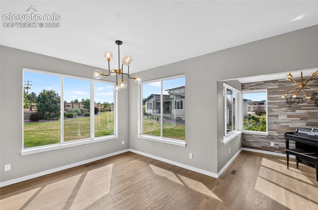 Image 10 of 50: Spacious interior room featuring wood-finish flooring and light gray walls