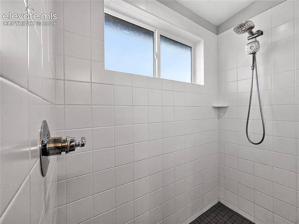 Image 19 of 50: Shower featuring white tiled walls, a dual-head shower system, recessed she