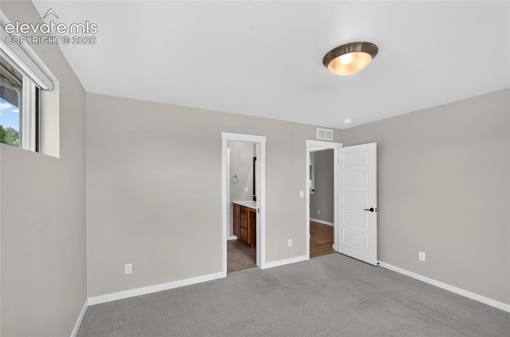 Image 22 of 50: Main floor bedroom with bath access Carpeted bedroom featuring light gray w