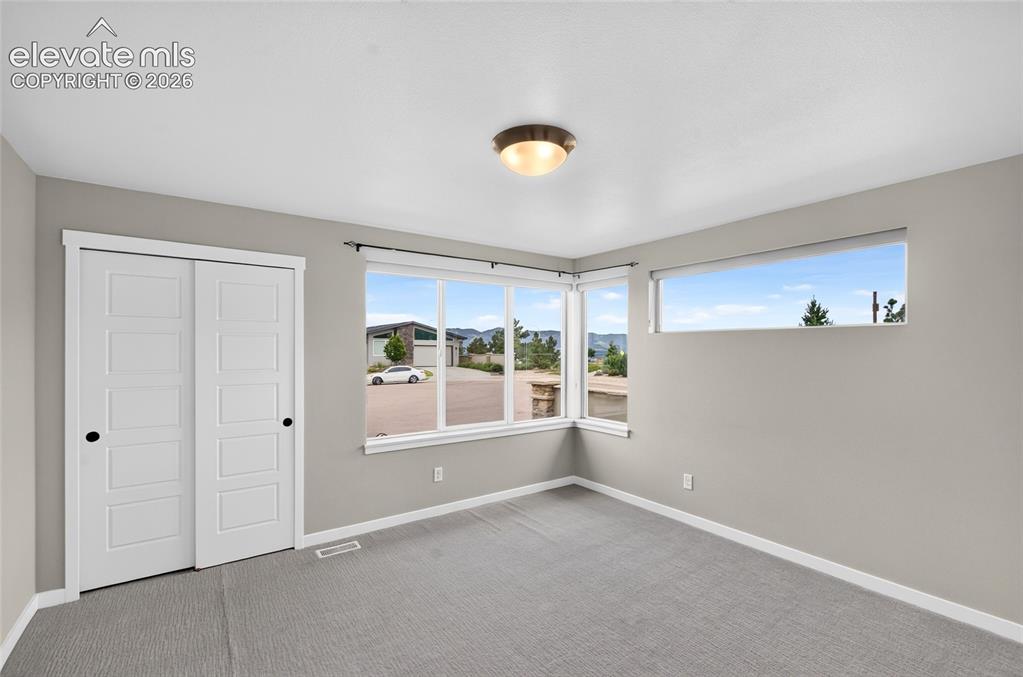 Image 26 of 50: Bright room featuring light grey walls, white trim, and grey carpet floorin