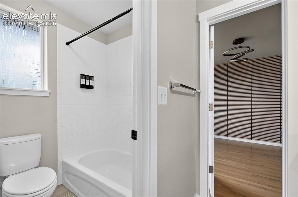 Image 28 of 50: Bathroom featuring a white bathtub with subway tile surround, black shower