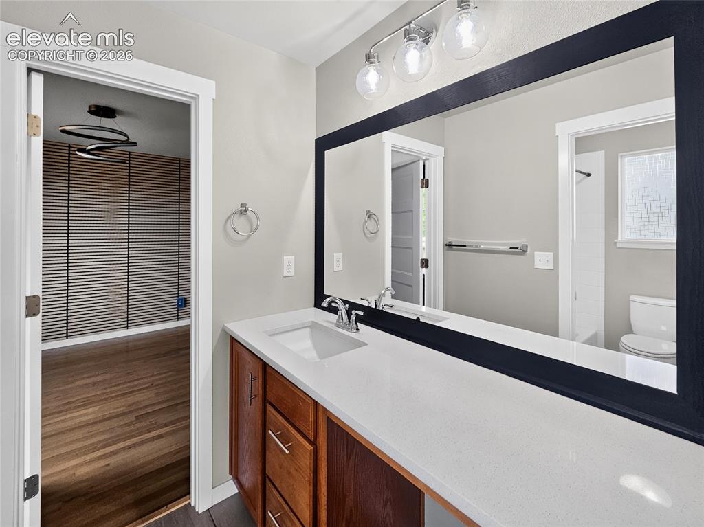 Image 29 of 50: Bathroom vanity featuring a single basin sink, white countertop, and wood-f