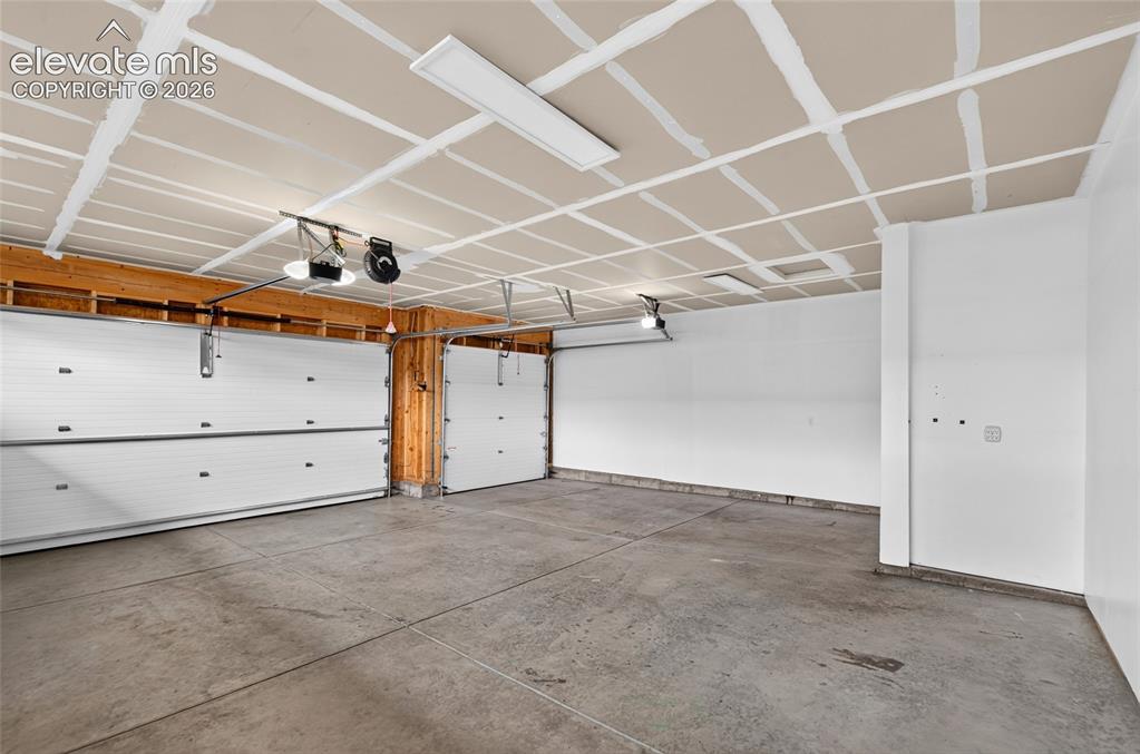 Image 31 of 50: Spacious 4 car tandem garage featuring a concrete floor, white walls, and e