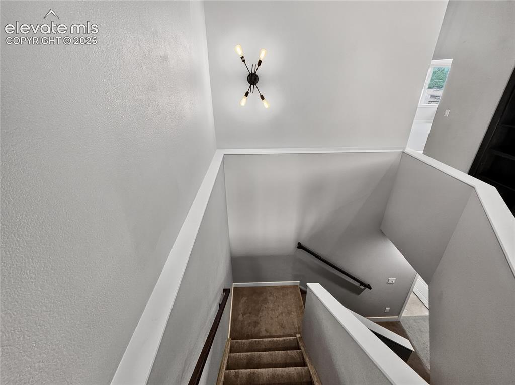 Image 32 of 50: Staircase featuring textured wall finishes, a modern ceiling light fixture,
