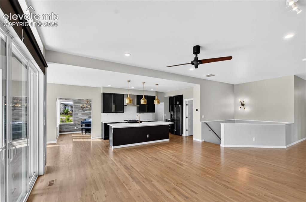 Image 5 of 50: Open-concept living area featuring wood-finish flooring, a contemporary kit
