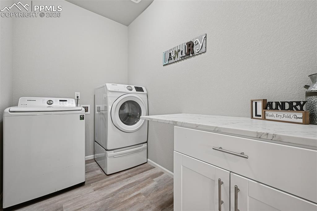 Image 19 of 32: SpaciouslLaundry area with cabinet space and folding area.